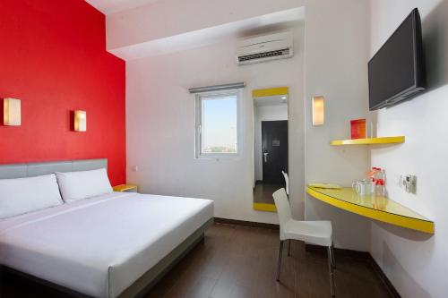 a bedroom with a bed and a desk and a tv at Amaris Hotel Pemuda Semarang in Semarang