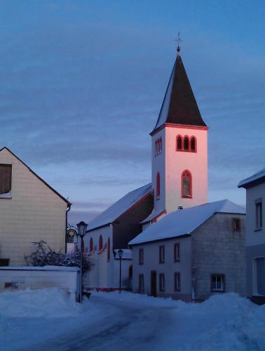a church with a clock tower in the snow at Ferienwohnung Ostwind in Schüller