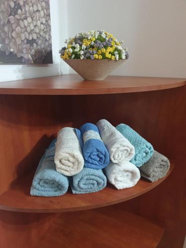 a bunch of towels on a shelf with a bowl of flowers at Cosy 2 rooms unit with a private garden in Eilat