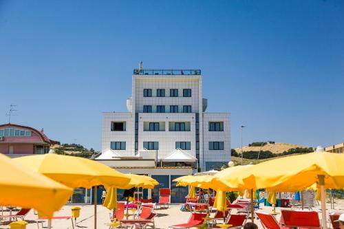 a building with yellow umbrellas in front of a beach at Hotel Royal in Fermo