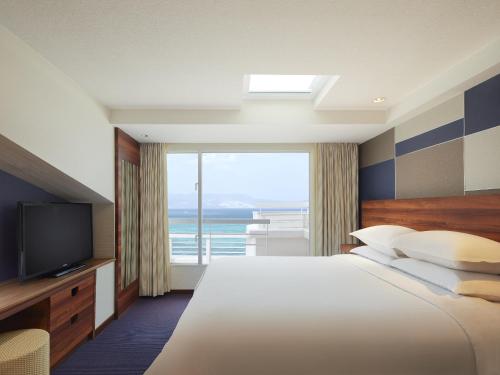 a hotel room with a large bed and a large window at Sheraton Okinawa Sunmarina Resort in Onna