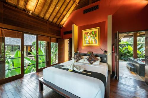 a bedroom with a large bed in a room with windows at Villa Vajra in Ubud