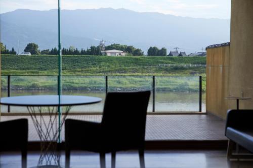 a table and chairs in a room with a large window at 原鶴の舞 in Asakura