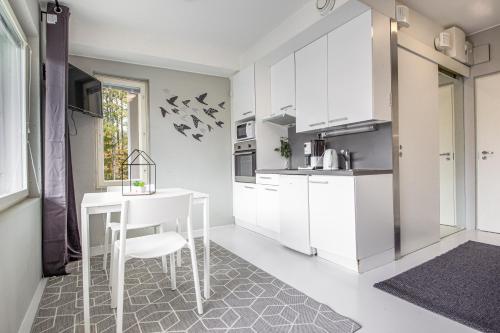 a kitchen with white cabinets and a white table at Spot Apartments Rajakylä in Vantaa