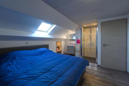 a bedroom with a blue bed and a window at Le Clocher in Nassogne