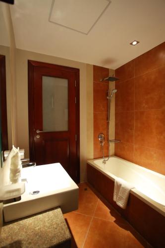 a bathroom with a tub and a toilet and a sink at Al Liwan Suites Rawdat Al Khail in Doha