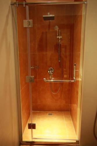 a shower with a glass door in a bathroom at Al Liwan Suites Rawdat Al Khail in Doha
