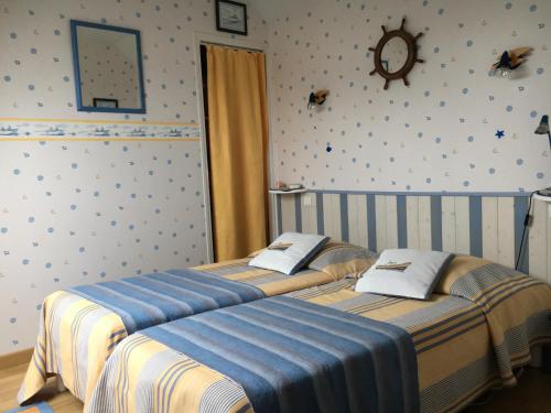 two twin beds in a bedroom with a clock on the wall at La Maison s'apelle le P'tit Nid in Granville