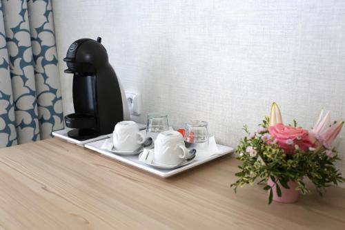 a coffee maker on a tray on a table with flowers at ASTORIA Hotel & Medical Spa in Karlovy Vary