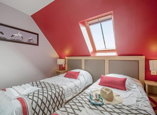 two beds in a room with red walls at Résidence Pierre & Vacances La Petite Venise in Colmar