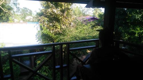 a person sitting on a balcony looking out the window at Song Lao Guesthouse in Thakhek