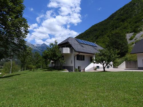 a house with solar panels on top of a green yard at Apartment Pri Leju in Srpenica