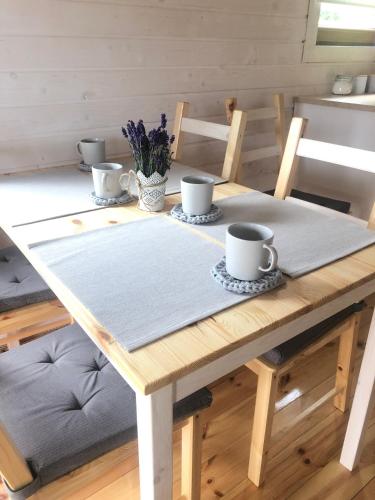 a wooden table with three cups and a napkin on it at Browarówka in Łomnica