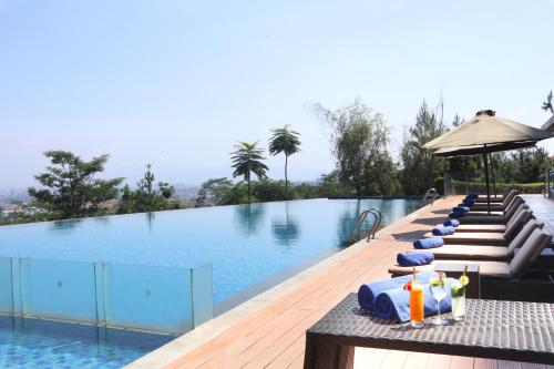 a pool with chairs and umbrellas next to a swimming pool at InterContinental Bandung Dago Pakar by IHG in Bandung