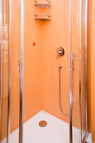 a shower stall in a bathroom with an orange wall at Hotel El Balear in Alghero