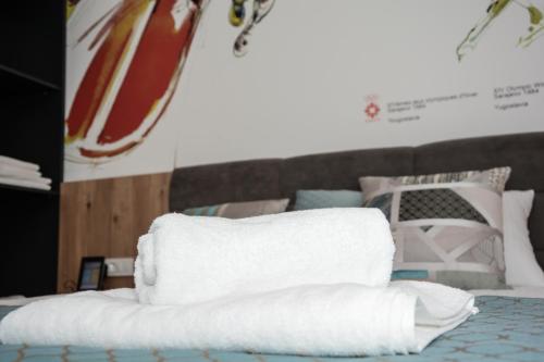 a stack of towels sitting on top of a bed at OLYMPIC 84 Apartments in Sarajevo