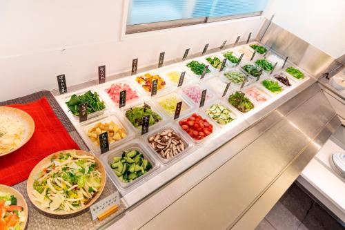 a buffet line of vegetables in plastic containers at DogoYaya in Matsuyama