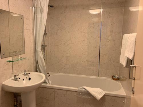 a bathroom with a sink and a bath tub and a sink at Alexandra Hotel in Ballater