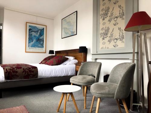 a bedroom with a bed and two chairs and a table at Entre Terre Et Mer in Honfleur