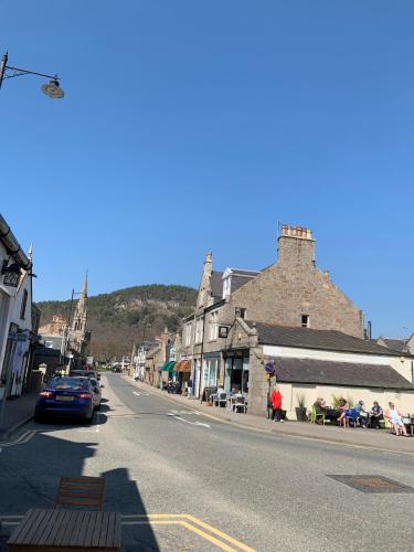 a street in a small town with people sitting on chairs at Alexandra Hotel in Ballater