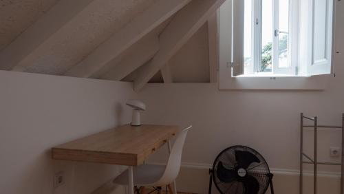 Zimmer mit einem Schreibtisch, einem Ventilator und einem Fenster in der Unterkunft APOSENTUS - Architect and design apartment in Porto