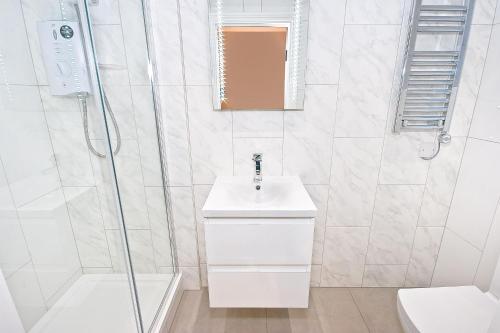 La salle de bains blanche est pourvue d'un lavabo et d'une douche. dans l'établissement Eldon Chambers Pod 6 by City Living London, à Londres