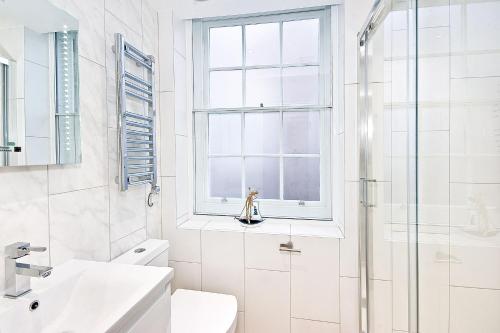 La salle de bains blanche est pourvue d'un lavabo et d'une douche. dans l'établissement Eldon Chambers Pod 5 by City Living London, à Londres