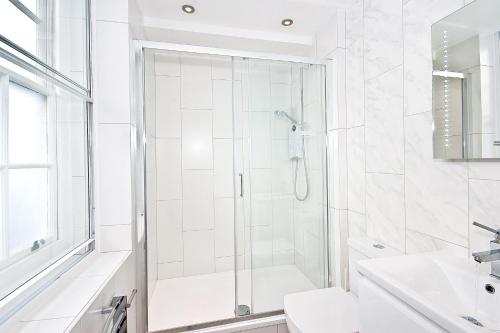 een witte badkamer met een douche en een wastafel bij Eldon Chambers Pod 3 by City Living London in Londen