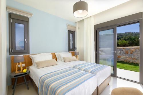 a bedroom with a bed and a large window at Apartment Tilio - New apartment with private pool 1400m from the beach in Rethymno