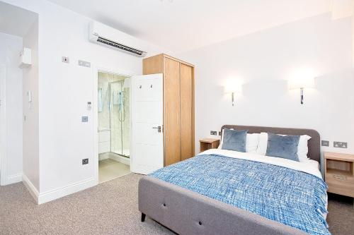 Dormitorio blanco con cama y armario en Eldon Chambers Pod 1 by City Living London en Londres