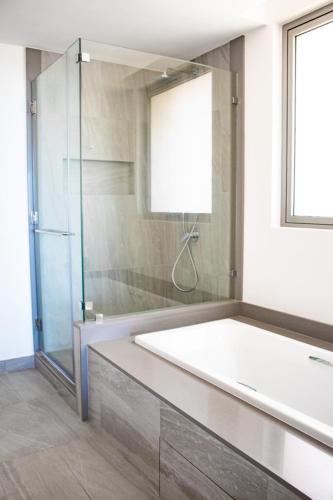 a bathroom with a tub and a glass shower at Manta Cove by Horizon Holidays in Tamarin