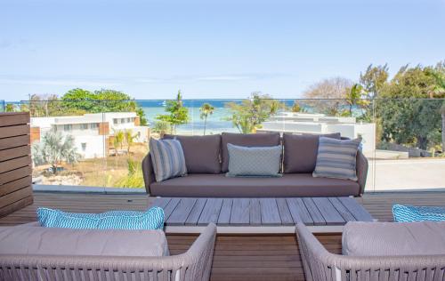 a patio with a couch and two chairs and the ocean at Manta Cove by Horizon Holidays in Tamarin