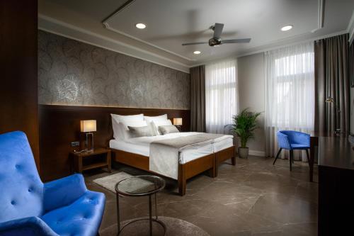 - une chambre avec un lit et une chaise bleue dans l'établissement Hotel Anna, à Beroun