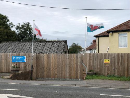 two flags flying in front of a wooden fence at 1 Ashford Road Guesthouse in Redhill