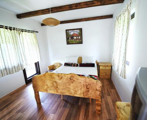 a bedroom with a bed with white walls and wooden floors at Etno selo Moj Zavičaj in Gornji Milanovac
