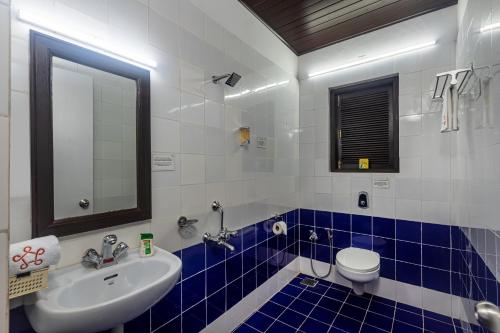 a bathroom with a sink and a toilet and a mirror at SaffronStays Blue Flag House, a 3-BDR beachfront villa in Hejamady in Mangalore