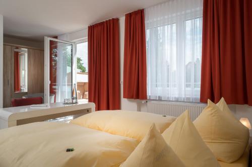 a bedroom with two beds and a window with red curtains at Hotel Nora in Bad Krozingen