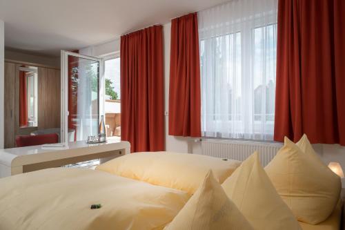 1 dormitorio con 2 camas y una ventana con cortinas rojas en Hotel Nora en Bad Krozingen