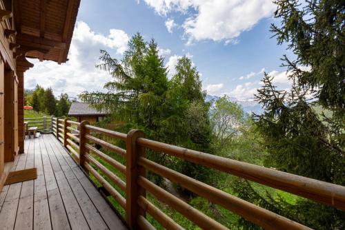 a wooden deck with a view of the mountains at Jacuzzi & Sauna | Chalet Teremok in La Tzoumaz