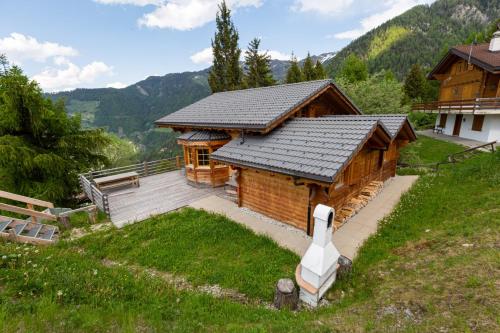 a large wooden house with a roof on a hill at Jacuzzi & Sauna | Chalet Teremok in La Tzoumaz