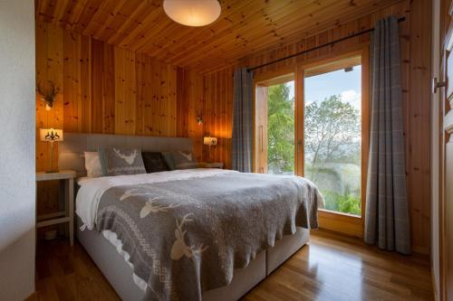 a bedroom with a bed and a large window at Jacuzzi & Sauna | Chalet Teremok in La Tzoumaz