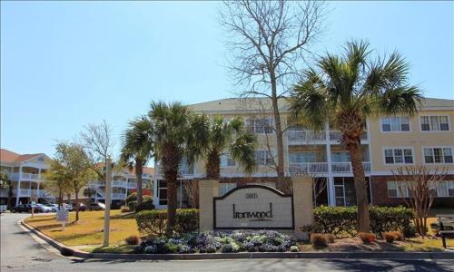 a sign in front of a hotel with palm trees at 1633 Ironwood Condo in Myrtle Beach