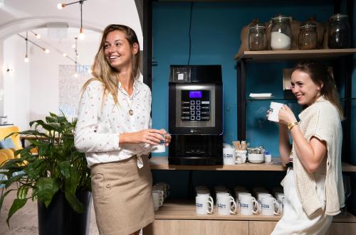 two women are standing in front of a microwave at Three Corners Hotel Anna in Budapest