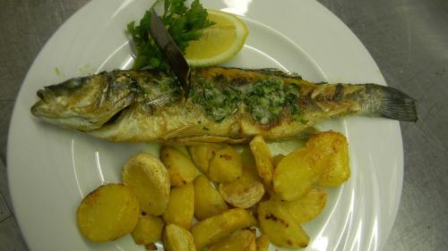 a fish on a plate with potatoes and a lemon at Hotel Krona Domžale in Domžale
