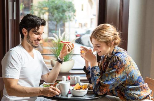 a man and a woman sitting at a table eating food at Three Corners Hotel Art in Budapest