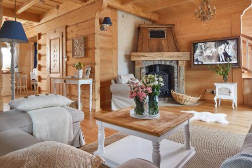 a living room with a fireplace and a table with flowers on it at Osada Maruszyna in Szaflary
