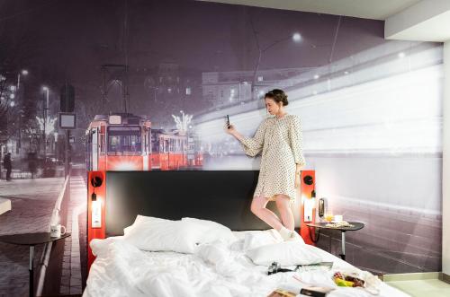 a woman is standing on top of a bed at Three Corners Hotel Anna in Budapest