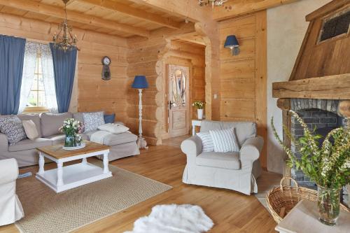 a living room with white furniture and a fireplace at Osada Maruszyna in Szaflary