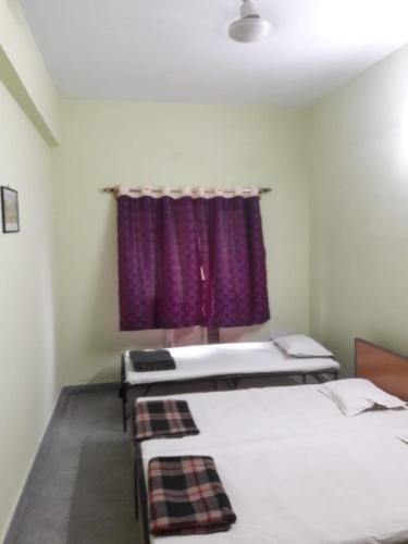 a room with two beds and a purple curtain at Capital Guest House in Kolkata