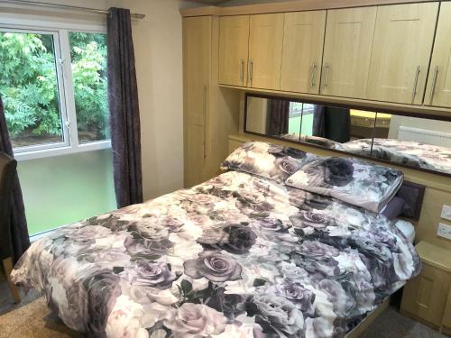 a bedroom with a bed with a floral comforter at Gold Standard Caravan on South View Park in Skegness